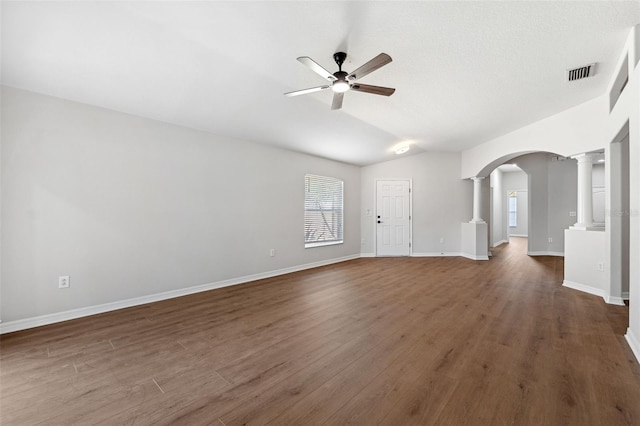 unfurnished living room with ornate columns, vaulted ceiling, dark hardwood / wood-style floors, and ceiling fan