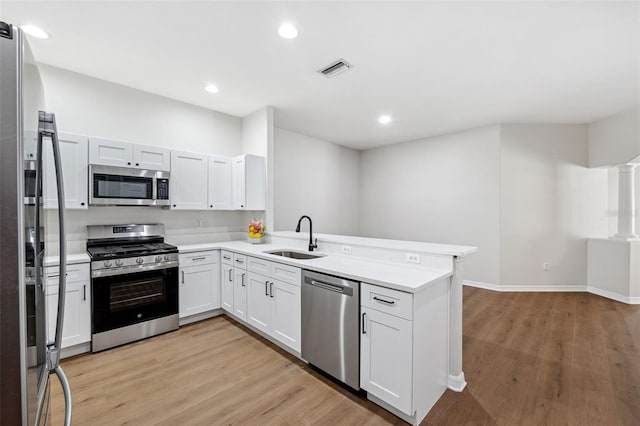 kitchen with stainless steel appliances, white cabinetry, sink, and kitchen peninsula