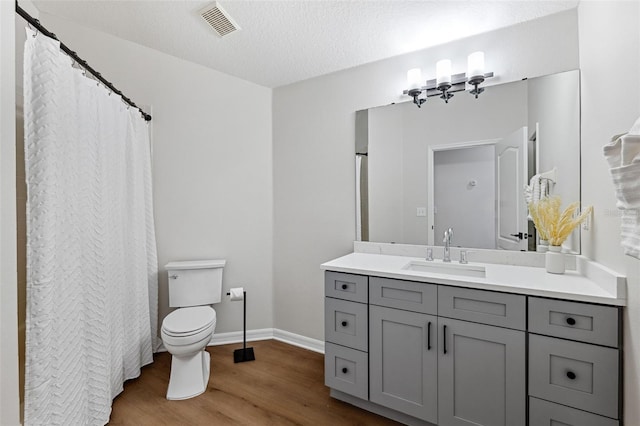 bathroom featuring vanity, a textured ceiling, wood-type flooring, and toilet