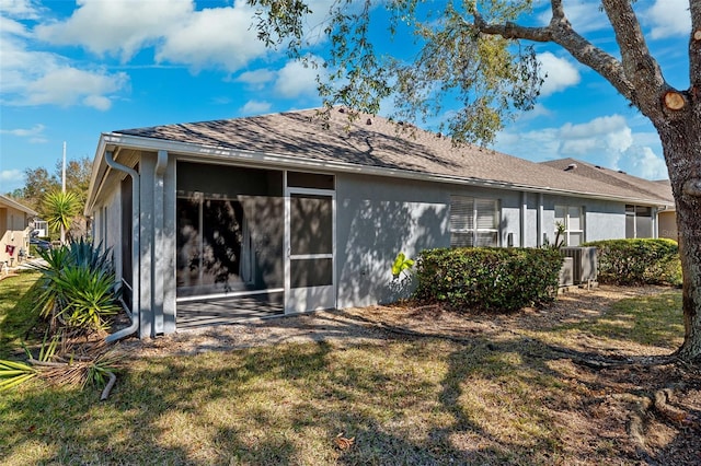 rear view of property featuring cooling unit, a sunroom, and a lawn