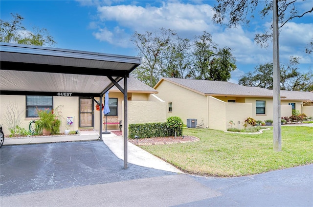 view of front of home featuring cooling unit, a front lawn, and a carport