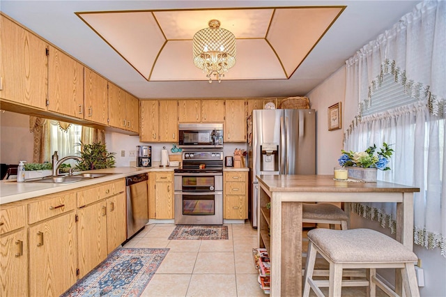 kitchen featuring light tile patterned flooring, a raised ceiling, sink, a notable chandelier, and stainless steel appliances