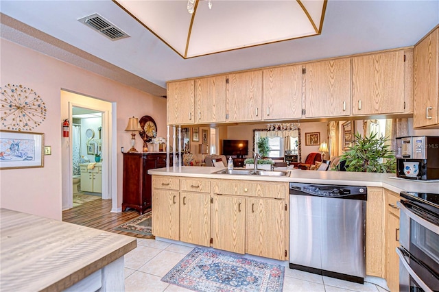 kitchen with stainless steel appliances, light brown cabinetry, kitchen peninsula, and sink