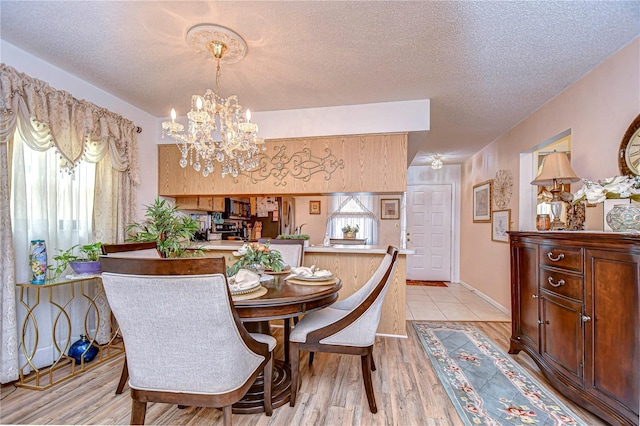 dining area with a notable chandelier, light hardwood / wood-style floors, and a textured ceiling