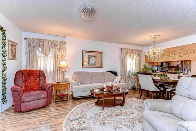 living room featuring a textured ceiling, light hardwood / wood-style flooring, a chandelier, and plenty of natural light