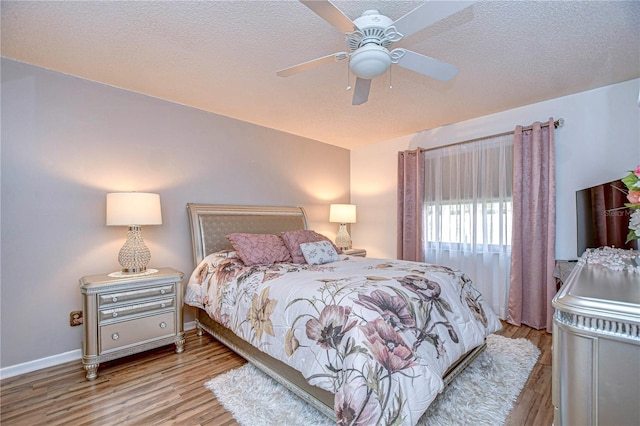 bedroom with ceiling fan, a textured ceiling, and light wood-type flooring