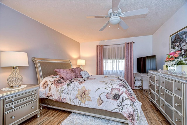 bedroom with vaulted ceiling, hardwood / wood-style floors, ceiling fan, and a textured ceiling