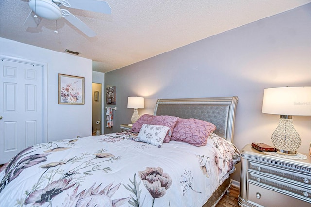 bedroom featuring ceiling fan, dark hardwood / wood-style flooring, and a textured ceiling