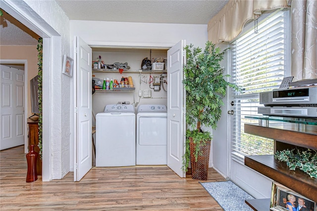 laundry area with light hardwood / wood-style flooring, washer and dryer, and a textured ceiling