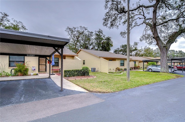 view of front of property with a carport, central AC, and a front lawn