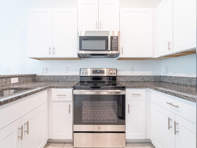 kitchen featuring white cabinetry, appliances with stainless steel finishes, and dark stone counters