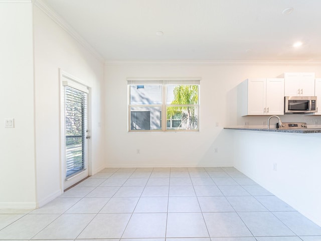 kitchen with light tile patterned floors, crown molding, plenty of natural light, and white cabinets