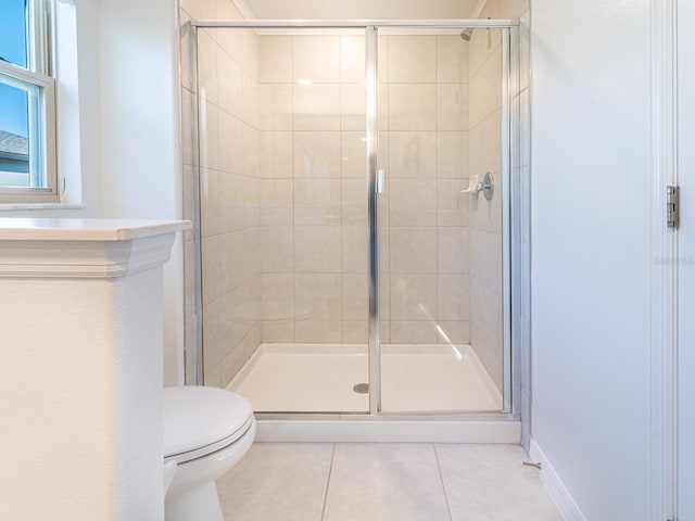 bathroom featuring tile patterned flooring, a shower with shower door, and toilet