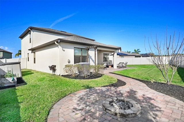 back of house featuring a yard, a fire pit, and a patio