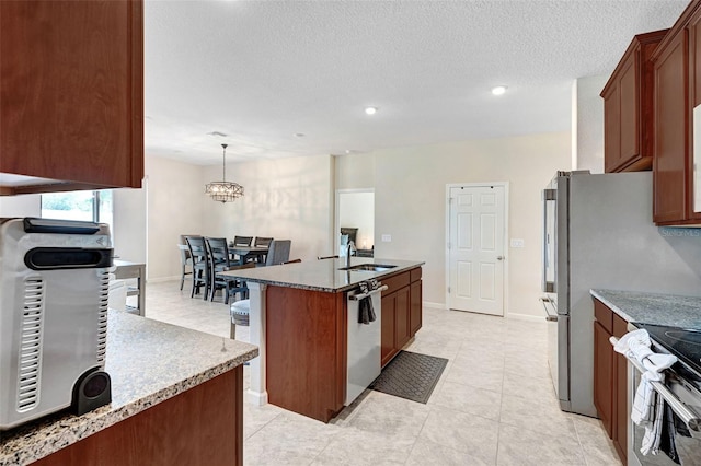 kitchen with sink, decorative light fixtures, a textured ceiling, an island with sink, and stainless steel appliances