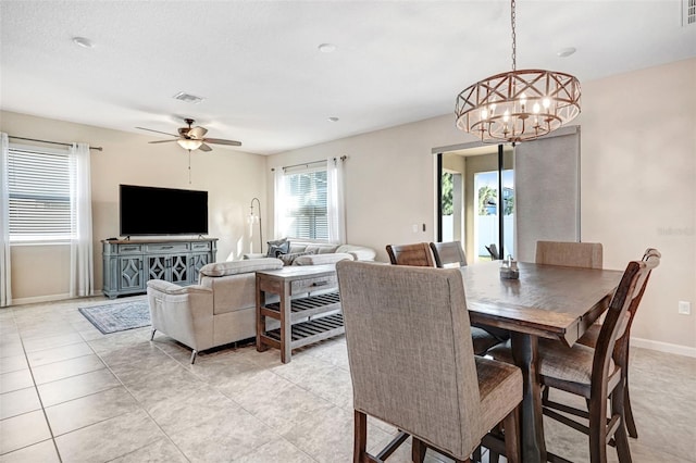 dining room with light tile patterned floors and ceiling fan with notable chandelier