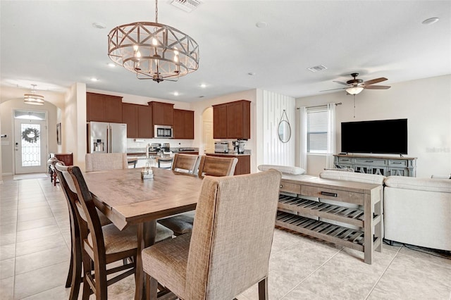 tiled dining space with ceiling fan with notable chandelier