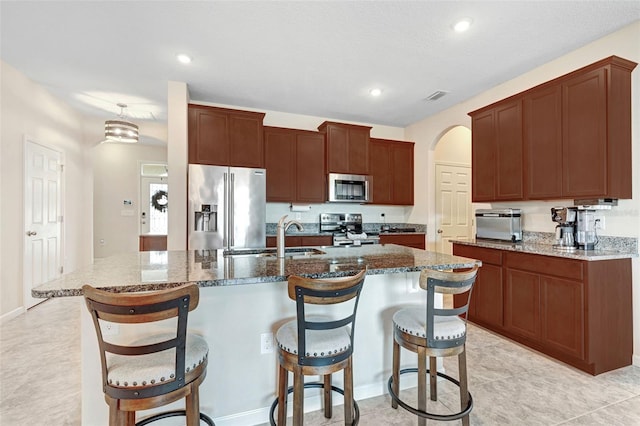 kitchen featuring sink, a center island with sink, a breakfast bar area, and appliances with stainless steel finishes