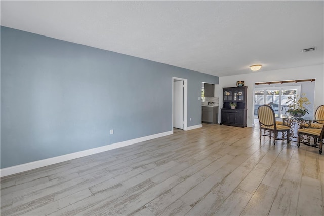 unfurnished living room with a textured ceiling and light hardwood / wood-style flooring