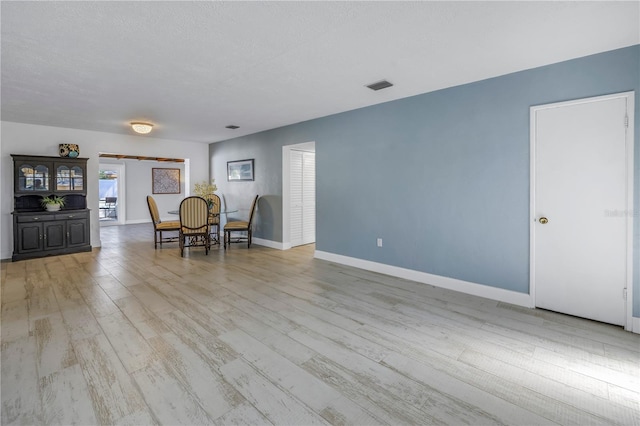 interior space featuring a textured ceiling and light hardwood / wood-style floors