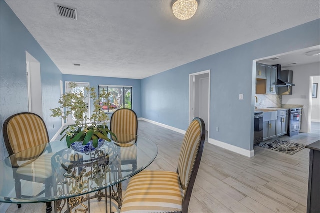 dining space featuring a textured ceiling and light hardwood / wood-style floors