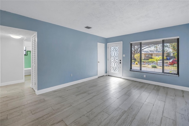 unfurnished room with light wood-type flooring and a textured ceiling