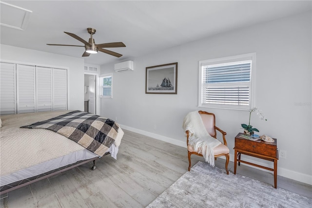 bedroom with ceiling fan, light wood-type flooring, a closet, and an AC wall unit