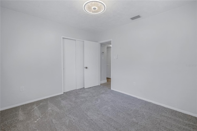 unfurnished bedroom with carpet, a textured ceiling, and a closet