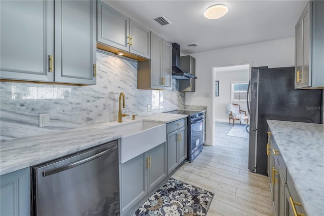 kitchen featuring stainless steel appliances, tasteful backsplash, gray cabinetry, and wall chimney exhaust hood