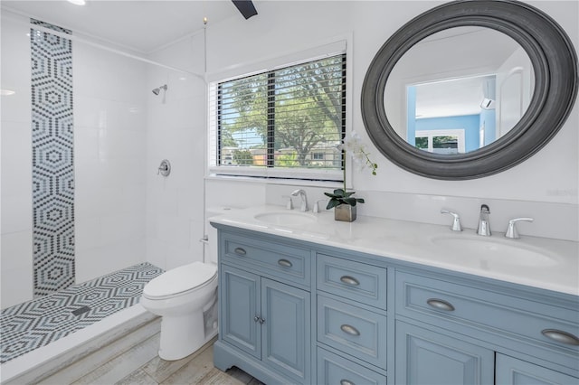 bathroom featuring hardwood / wood-style floors, vanity, a tile shower, and toilet