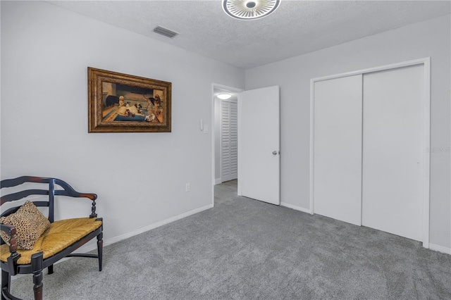 sitting room featuring carpet flooring and a textured ceiling