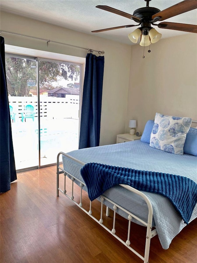 bedroom with hardwood / wood-style flooring, ceiling fan, access to exterior, and a textured ceiling