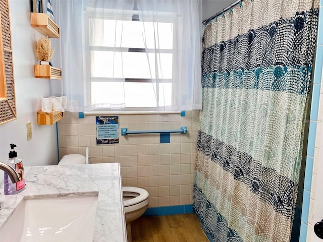 bathroom featuring hardwood / wood-style flooring, tile walls, vanity, curtained shower, and toilet