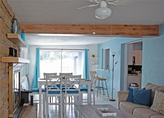 dining space with ceiling fan, beam ceiling, a textured ceiling, and light tile patterned floors