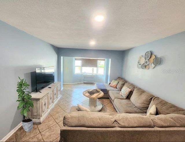 living area featuring a textured ceiling, light tile patterned flooring, and baseboards