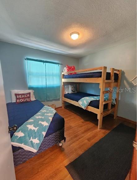 bedroom with a textured ceiling and wood finished floors