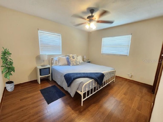 bedroom with baseboards, multiple windows, wood finished floors, and a ceiling fan