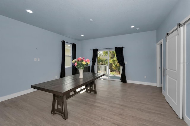 dining room with a barn door and light wood-type flooring