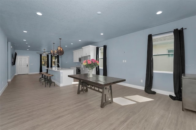 dining area with sink, light hardwood / wood-style flooring, and a textured ceiling