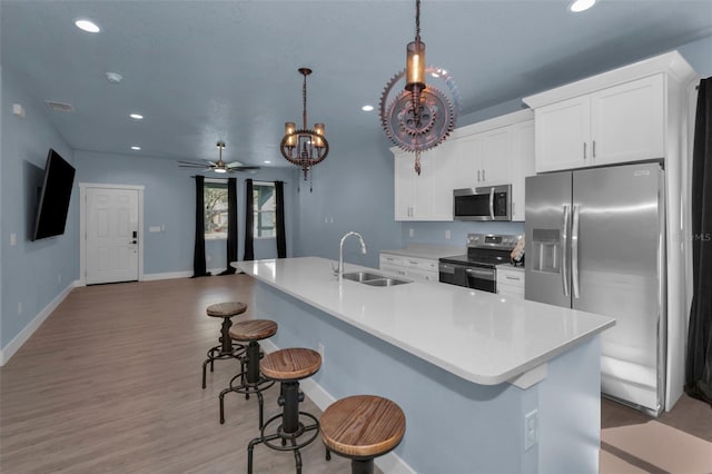 kitchen with stainless steel appliances, decorative light fixtures, a kitchen island with sink, and sink