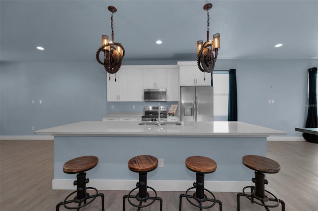 kitchen featuring hanging light fixtures, appliances with stainless steel finishes, sink, and a large island with sink