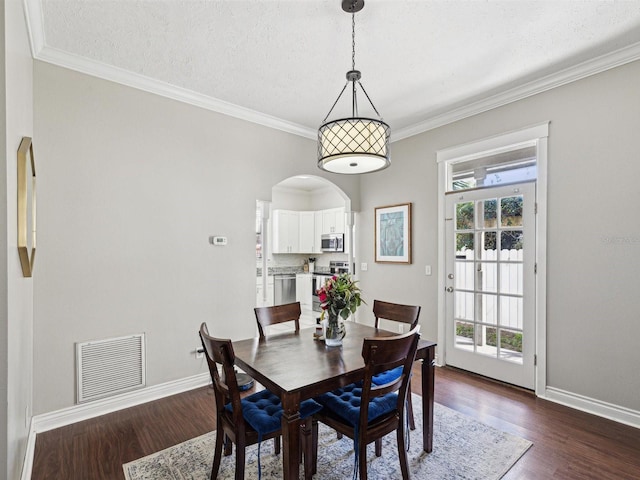 dining area featuring a textured ceiling, dark wood-type flooring, and crown molding