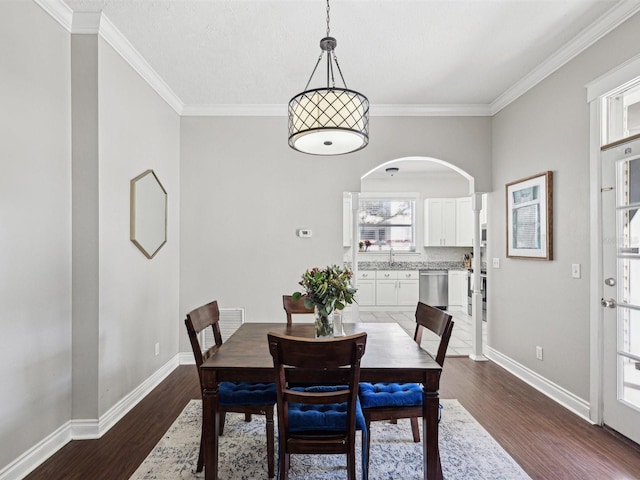 dining room with sink, ornamental molding, and dark hardwood / wood-style floors