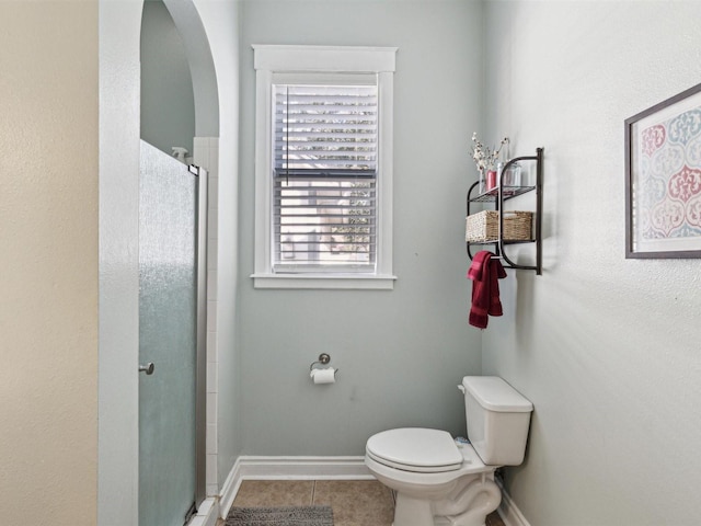 bathroom featuring tile patterned flooring, toilet, and walk in shower