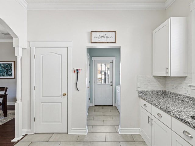 kitchen featuring light tile patterned floors, crown molding, white cabinets, light stone countertops, and tasteful backsplash