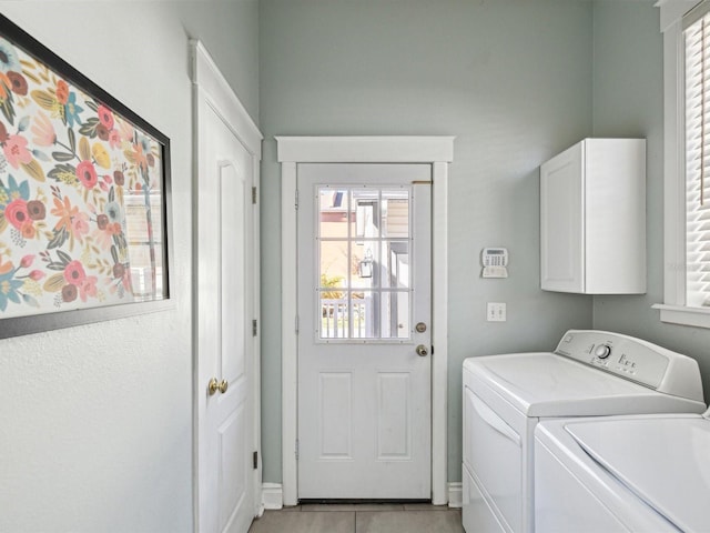 laundry room with light tile patterned floors, washer and clothes dryer, and cabinets