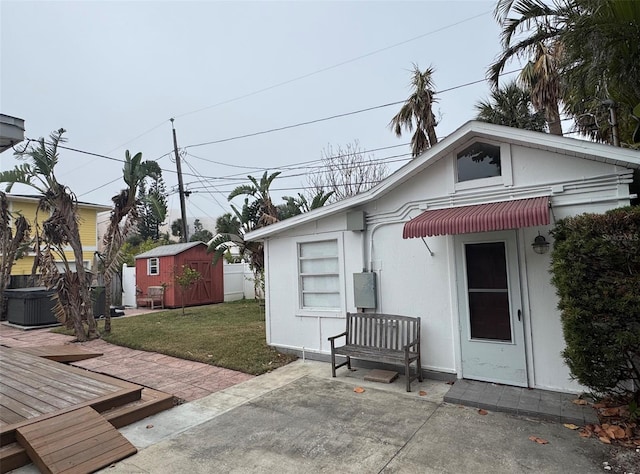 exterior space with a storage unit, a deck, a patio area, and a front yard