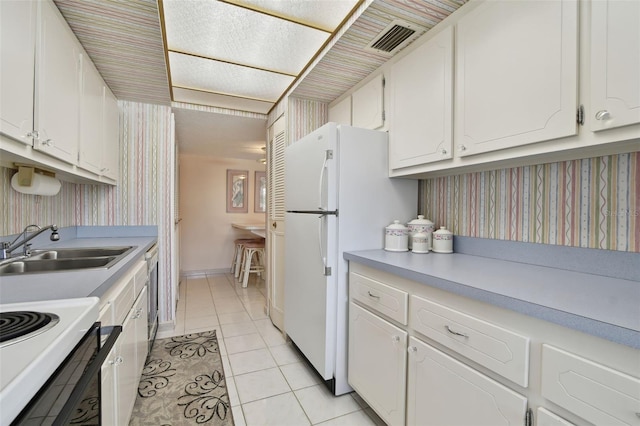 kitchen with dishwashing machine, sink, light tile patterned floors, white refrigerator, and white cabinets