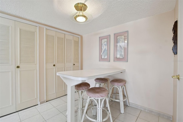 dining space featuring light tile patterned floors and a textured ceiling