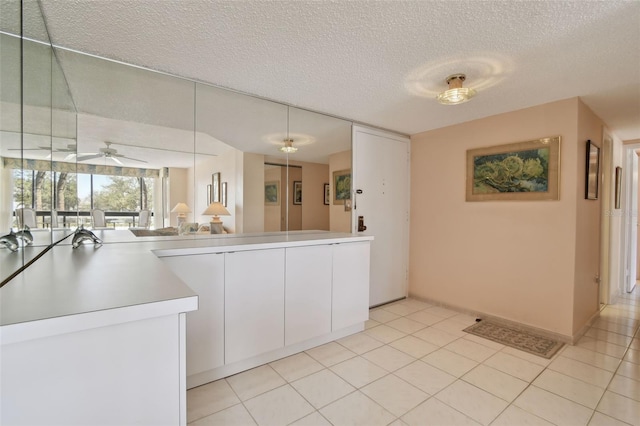 kitchen with ceiling fan, light tile patterned floors, white cabinets, and a textured ceiling